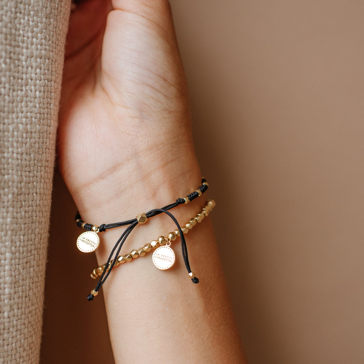 Close-up of a wrist wearing two bracelets on a neutral background