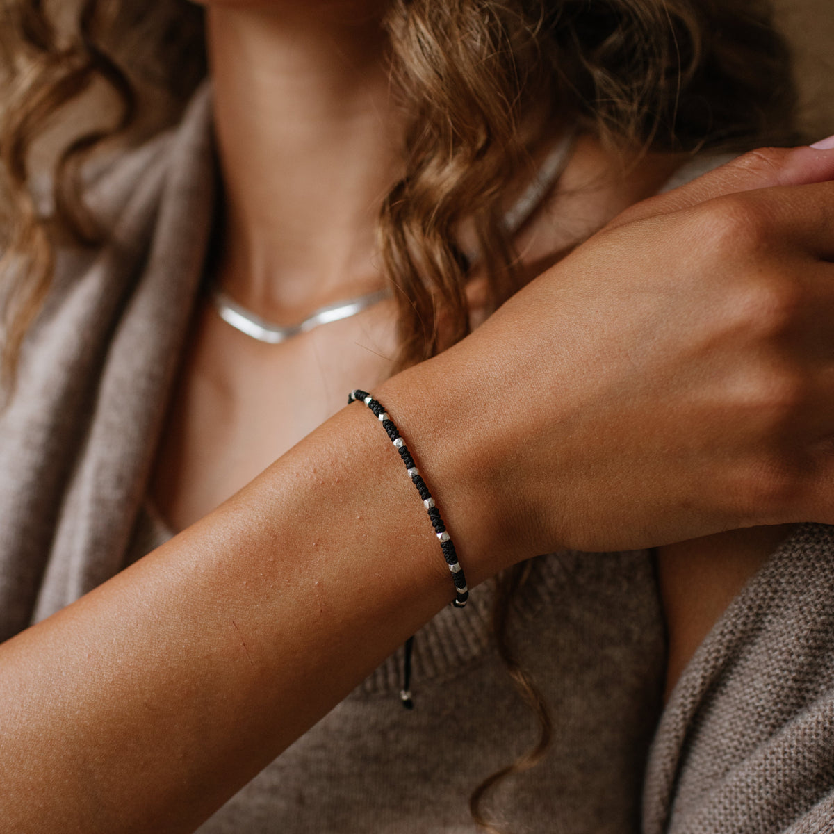 Close-up of a person wearing a bracelet with a neutral background