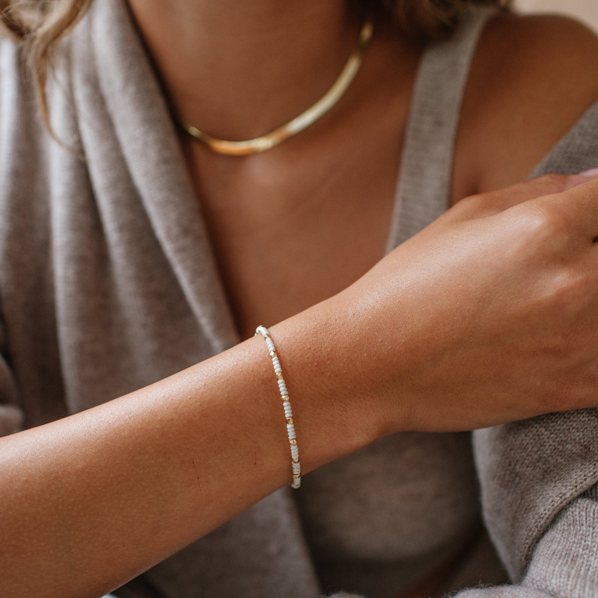 Close-up of a person wearing a gold necklace and bracelet.