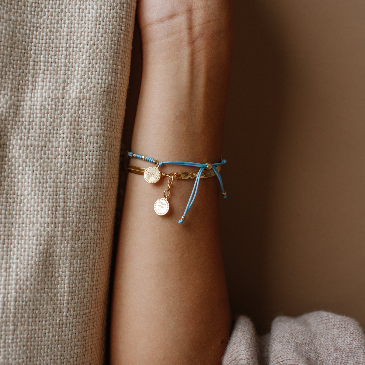 Close-up of a wrist wearing a blue bracelet with gold accents on a neutral background