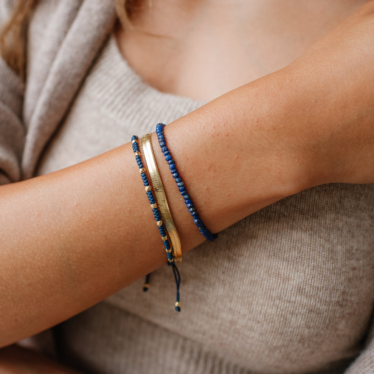 Close-up of a person&#39;s arm wearing two bracelets on a neutral background