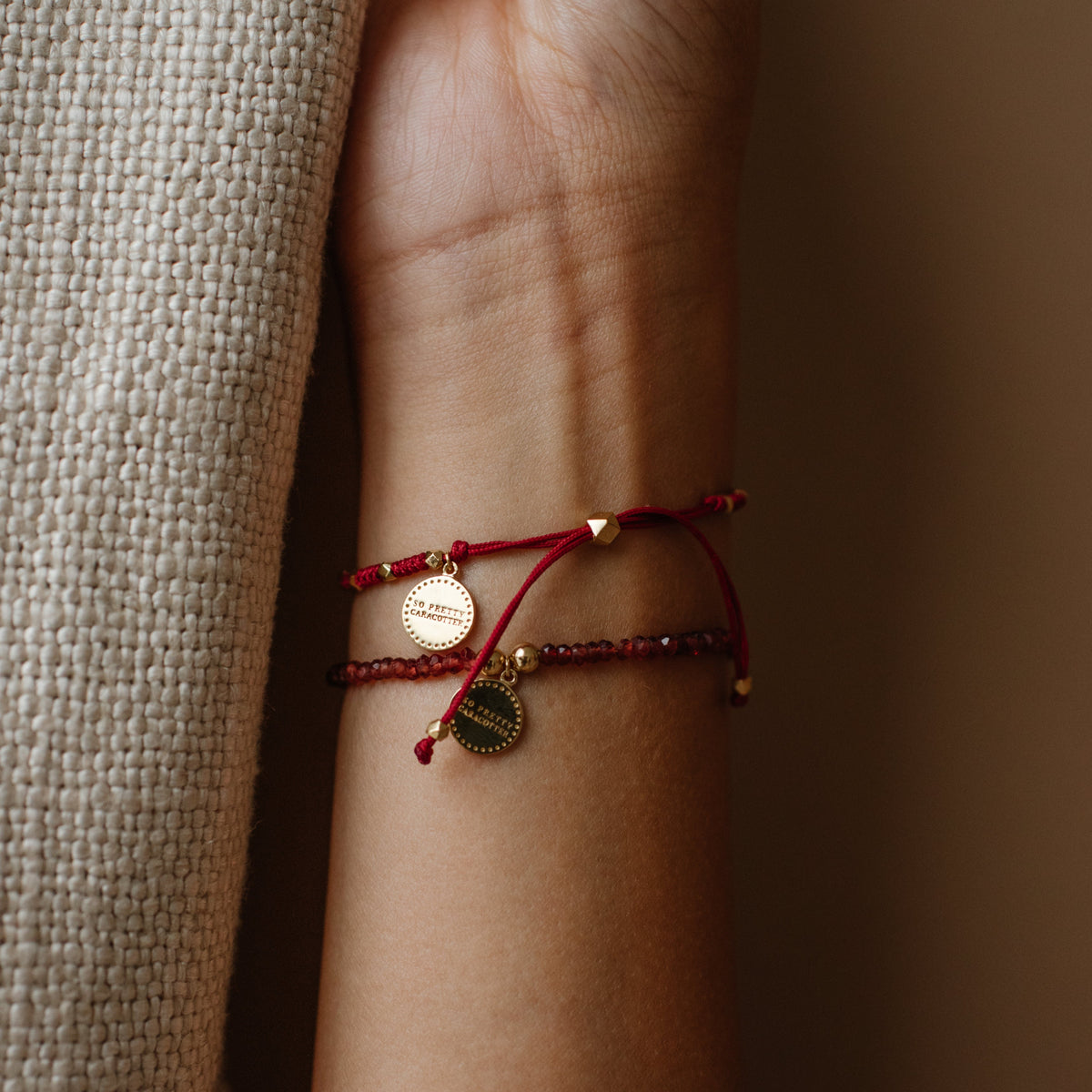 Close-up of a wrist wearing a red bracelet with gold accents on a blurred background