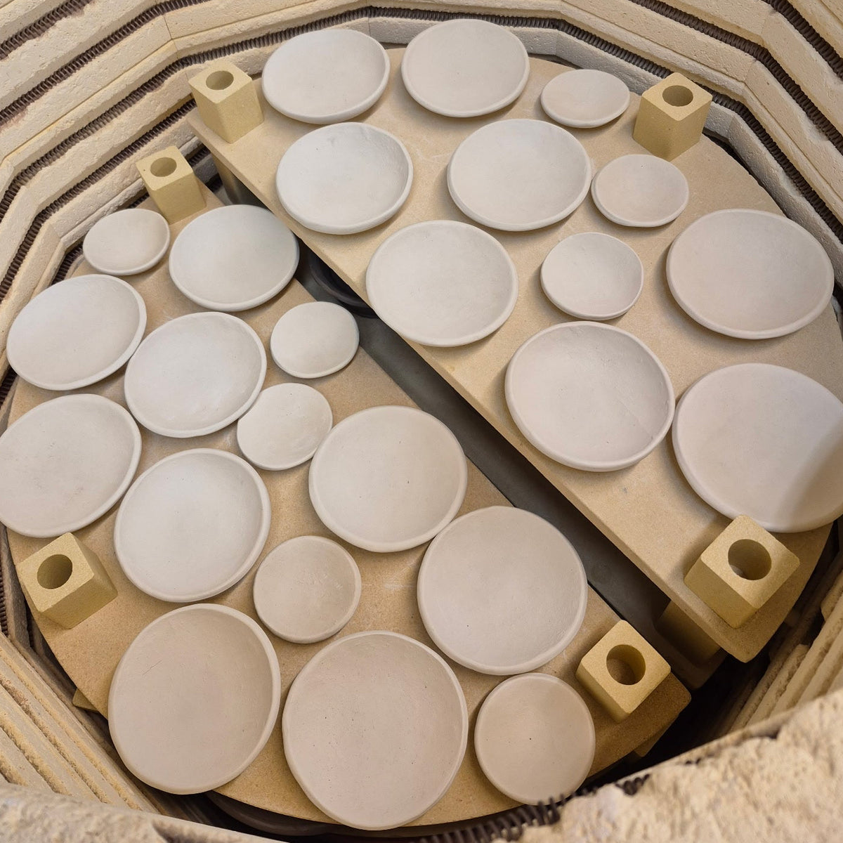 Clay plates of various sizes arranged in a kiln