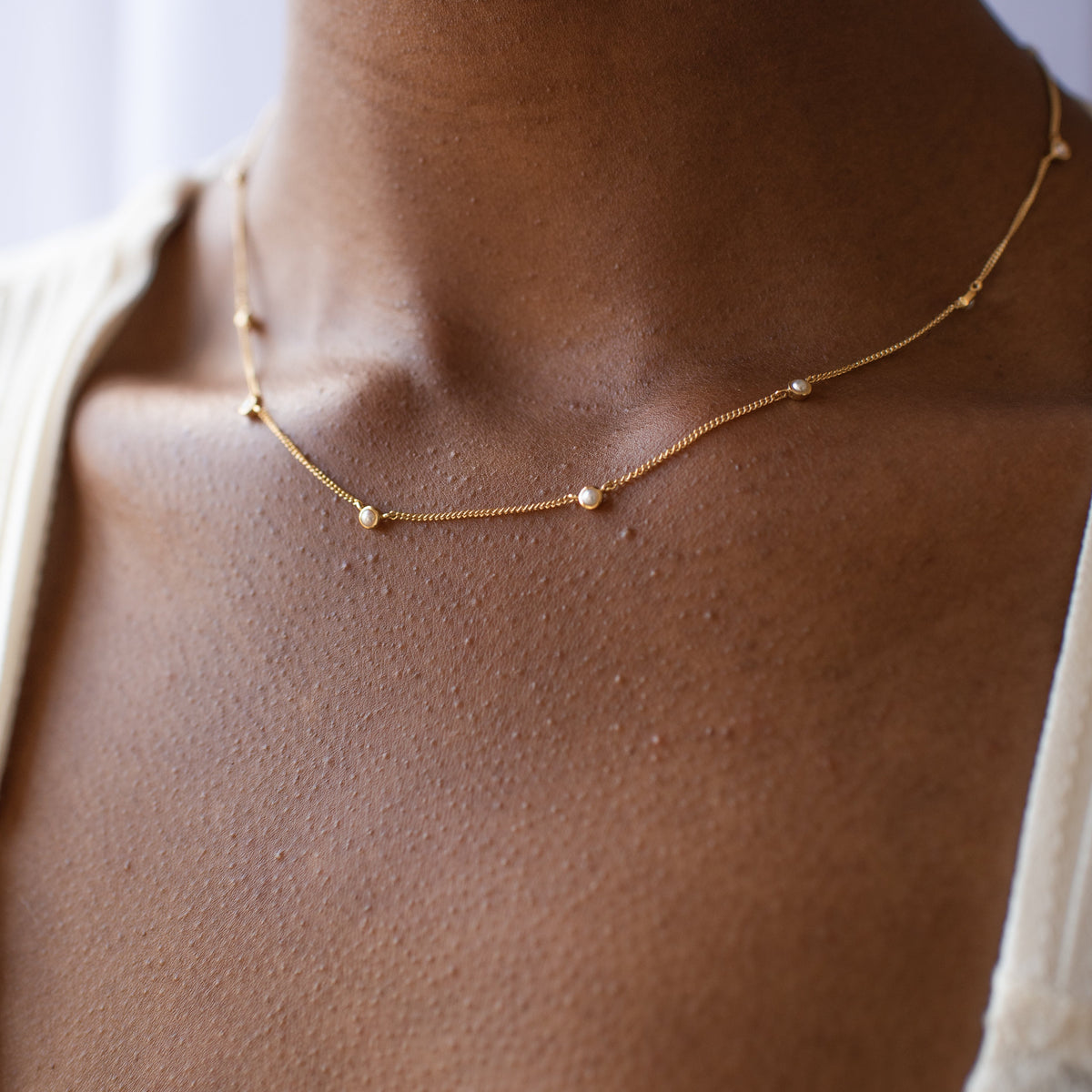 Gold necklace on a person's neck with a blurred background